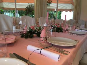 einen Tisch mit Gläsern, Tellern und Blumen darauf in der Unterkunft Hotel Beau Rivage Pineta in Lido di Jesolo