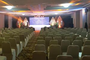 a room with chairs and a screen with a stage at Grand Keisha Yogyakarta in Yogyakarta