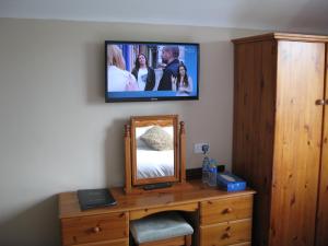 a tv on a wall above a dresser with a mirror at Firtrees Bed & Breakfast in Rostrevor