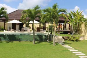 a house with a swimming pool and palm trees at Uma Kama Villa in Ubud