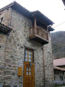 un edificio de piedra con puerta de madera y balcón en Casa Rural La Torre de Espinama, en Espinama