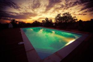 a large swimming pool with a sunset in the background at Alon Bagalil in Kahal