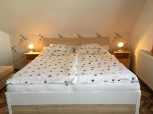 Un dormitorio con una cama blanca con dos lámparas sobre dos mesas. en Gitta Apartman, en Bük