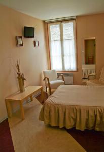 a bedroom with a bed and a table and a chair at Hôtel Bertrand in Bar-le-Duc