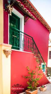 un edificio rojo con una puerta verde y un balcón en Casa di Stassa, en Parga