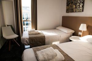 una camera d'albergo con tre letti e una finestra di Wallada Centro a Cordoba