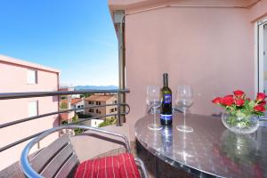 a table with two wine glasses and flowers on a balcony at Apartment Lola Maria in Zadar