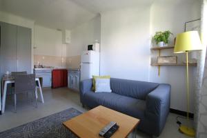a living room with a blue couch and a kitchen at Au dessus des platanes in Carpentras