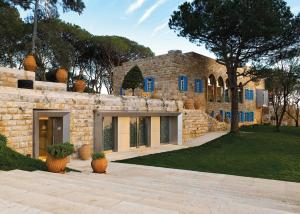 a stone house with blue windows and a yard at Hotel Al Bustan in Beit Meri