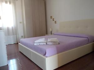 Una cama blanca con sábanas moradas y toallas. en Mare Natura, en Castelsardo