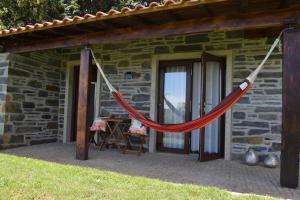 uma rede pendurada fora de uma casa de pedra em Quinta da Boa Ventura em Brangança