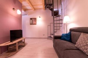 salon z kanapą i telewizorem w obiekcie Aura Ortigia Apartments w Syrakuzach