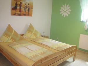 Ce lit se trouve dans une chambre dotée d'un mur vert. dans l'établissement Haus Alexandra, à Rust