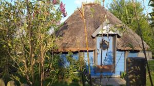 une maison au toit de chaume avec une porte bleue dans l'établissement Aux murmures de la nature, à Honfleur