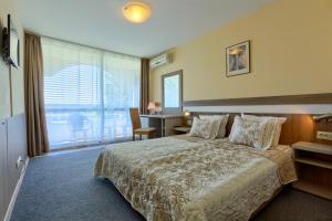 a hotel room with a large bed and a desk at Hotel Naslada in Balchik +57 photos
