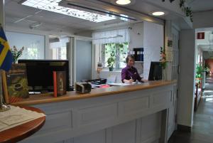 a woman sitting at a counter in a store at Sigtunastiftelsen Hotell & Konferens in Sigtuna