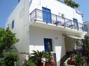 a white building with blue doors and a balcony at Vakhos in Naxos Chora