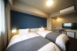 um quarto de hotel com duas camas e uma televisão de ecrã plano em Dormy Inn EXPRESS Sendai Seaside em Sendai