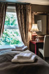 een slaapkamer met een bed, een raam en een stoel bij Tir y Coed Country House in Conwy