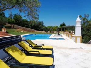 a group of yellow lounge chairs next to a swimming pool at Quinta do Julião in Tavira
