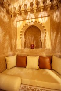 a couch sitting in a room with a wall at Riad Dar Haven in Tamraght Ou Fella