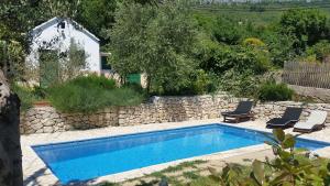 a swimming pool with two chairs and a stone wall at Villa Pool Mansion Salonae in Solin
