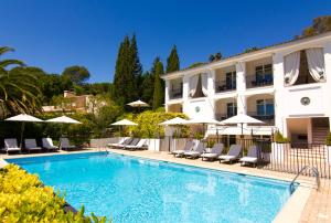 a pool in front of a building with chairs and umbrellas at Hotel les Vergers de Saint Paul in Saint Paul de Vence