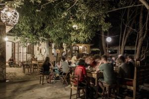 a group of people sitting at tables in a restaurant at night at Caracolito Hostal in Las Peñitas