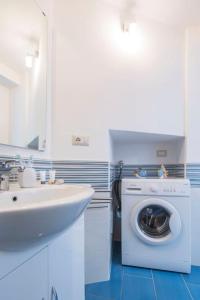 een witte badkamer met een wasmachine en een wastafel bij Casa Vuolo in Atrani