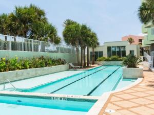 a swimming pool with palm trees and a building at Galveston Luxury High Rise Oceanfront in Galveston