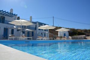 einen Pool mit Stühlen und Sonnenschirmen vor einem Haus in der Unterkunft White Blue Houses & Apartments Paros in Parikia