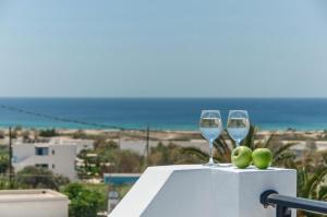 two glasses of wine sitting on a ledge with the ocean at Villa Adriana Hotel in Agios Prokopios