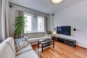 a living room with a couch and a flat screen tv at White 76. Gdynia Śródmieście in Gdynia