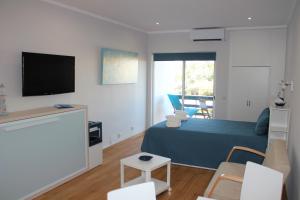 a bedroom with a bed and a tv and chairs at Vilamoura Dolphin Studio in Vilamoura