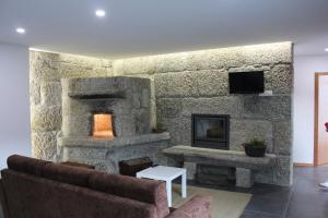 a living room with a stone wall with a fireplace at Casa do Sobreira in Vieira do Minho