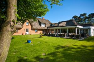 une grande maison en briques avec une cour d'herbe dans l'établissement Kathmeyers Landhaus Godewind, à Sankt Peter-Ording