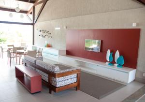 a dining room with a bench and a red wall at Apto Oka Beach Residence in Porto De Galinhas