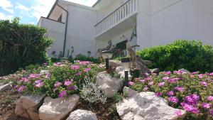 a garden with pink flowers and rocks in front of a building at Apartments Anastazija in Pag +55 photos