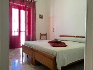 マティーノにあるCasa nel Salento da Graceのベッドルーム1室(ベッド1台付)、赤いカーテン付きの窓が備わります。