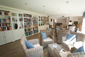 uma biblioteca com cadeiras de vime e livros em Kathmeyers Landhaus Godewind em Sankt Peter-Ording