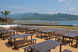 eine Reihe von Tischen und Bänken auf einem Deck in der Nähe des Wassers in der Unterkunft Sunrise Katsuura in Nachikatsuura