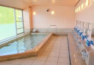 La salle de bains est pourvue de toilettes et d'une grande piscine. dans l'établissement Sunrise Katsuura, à Nachikatsuura