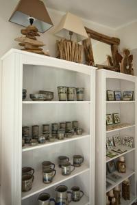 a white cabinet filled with lots of pottery at Kathmeyers Landhaus Godewind in Sankt Peter-Ording