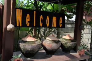 tres jarrones grandes en una mesa con un signo de bienvenida en Baan Aew Pai, en Pai