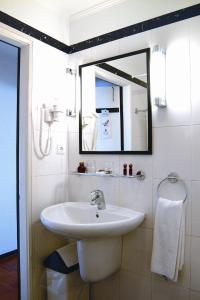 a bathroom with a sink and a mirror at Carcavelos Beach Hotel in Carcavelos