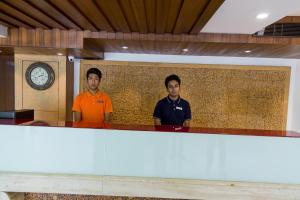 two men standing behind a counter in a room with a clock at Ginger Ahmedabad SG Road in Ahmedabad