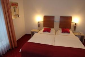 Habitación de hotel con 1 cama con 2 almohadas rojas en Hotel Restaurant Strümper Hof, en Meerbusch