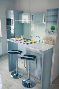 a white kitchen with two bar stools and a sink at Apartament Zeus in Zielona Góra