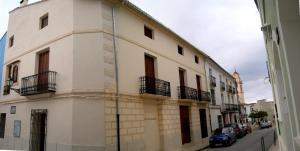 un bâtiment blanc avec balcon et voitures garées dans une rue dans l'établissement Ca Les Senyoretes, à Otos