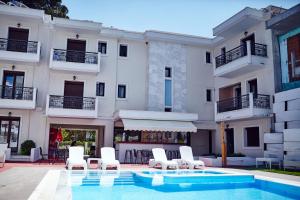 een hotel met een zwembad en witte stoelen en een gebouw bij Skiathos Somnia in Skiathos-stad
